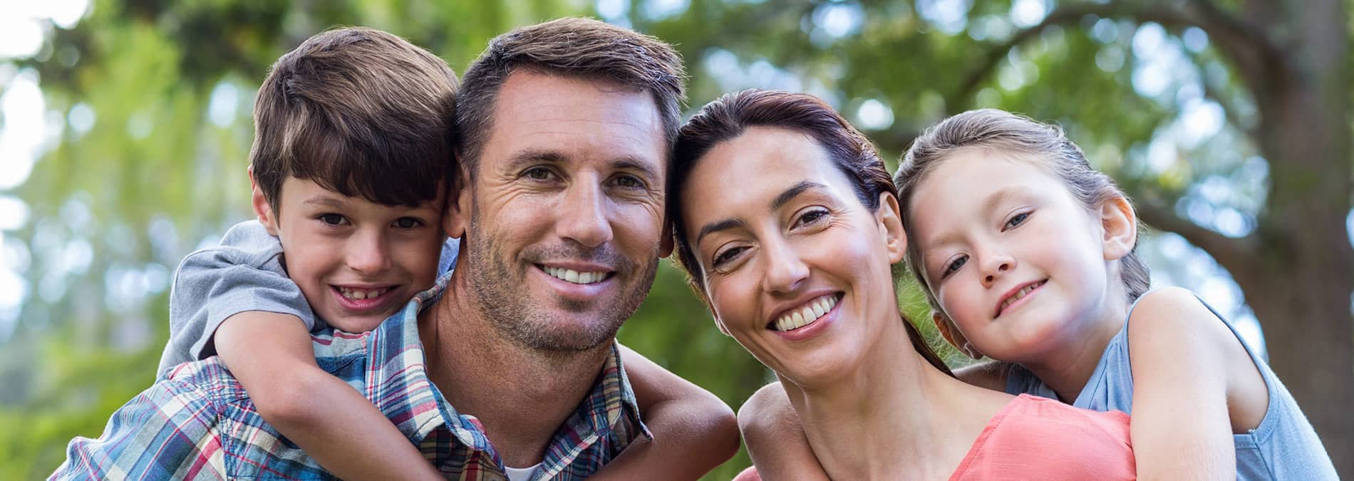 A family of four posing for a photo outdoors.