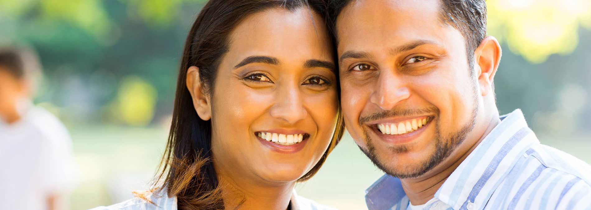A man and woman are smiling at the camera while standing close together, appearing happy and enjoying each other s company.
