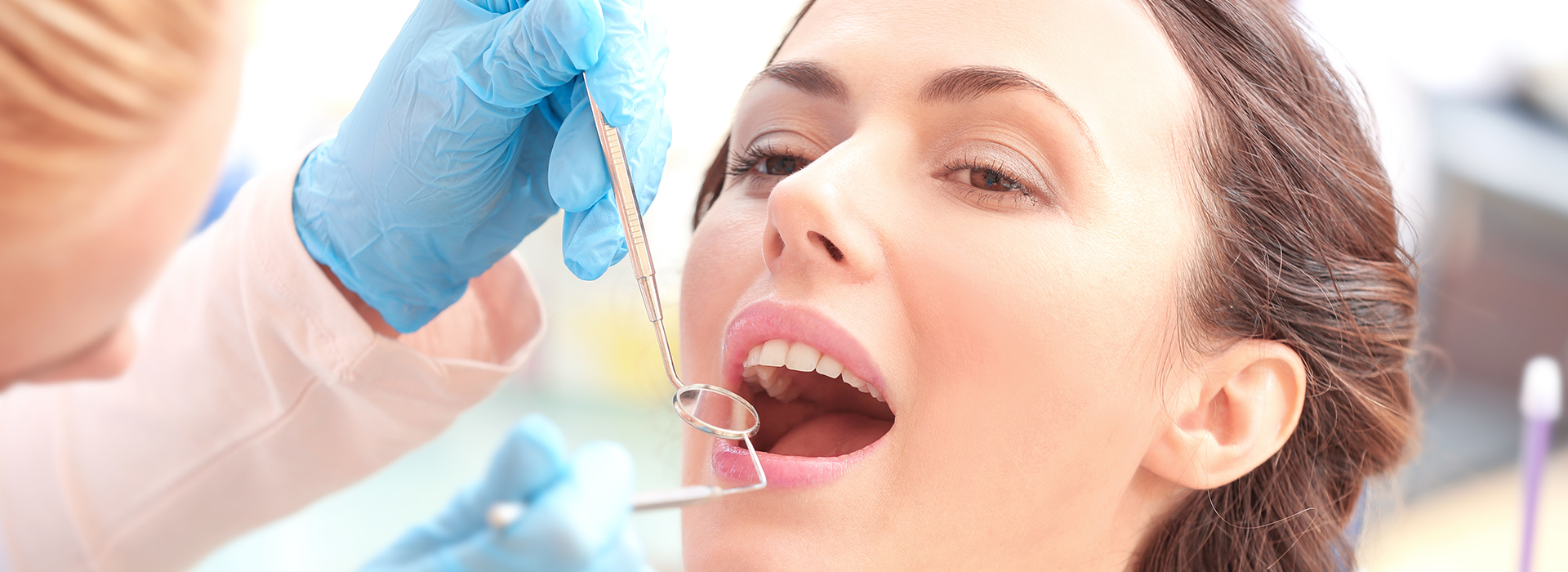 The image shows a person receiving dental care from a professional, with a focus on the dental work being performed.