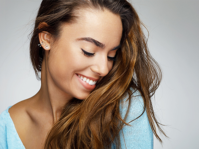 A smiling young woman with long hair posing for a portrait with a soft focus background.